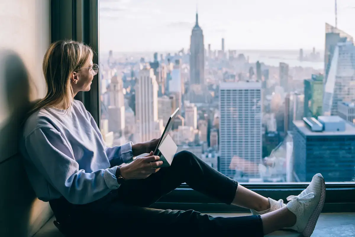 Travel nurse using a tablet while looking out at New York City