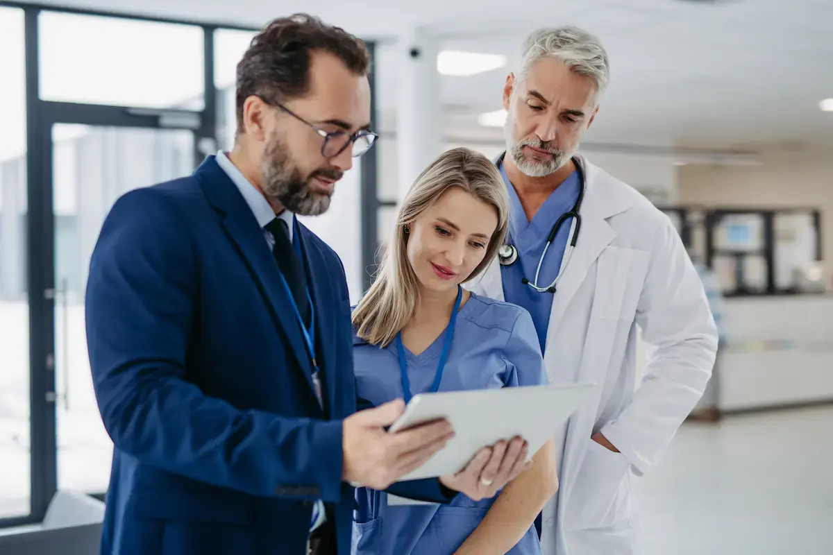 Businessman showing healthcare leaders a tablet while standing in a hospital