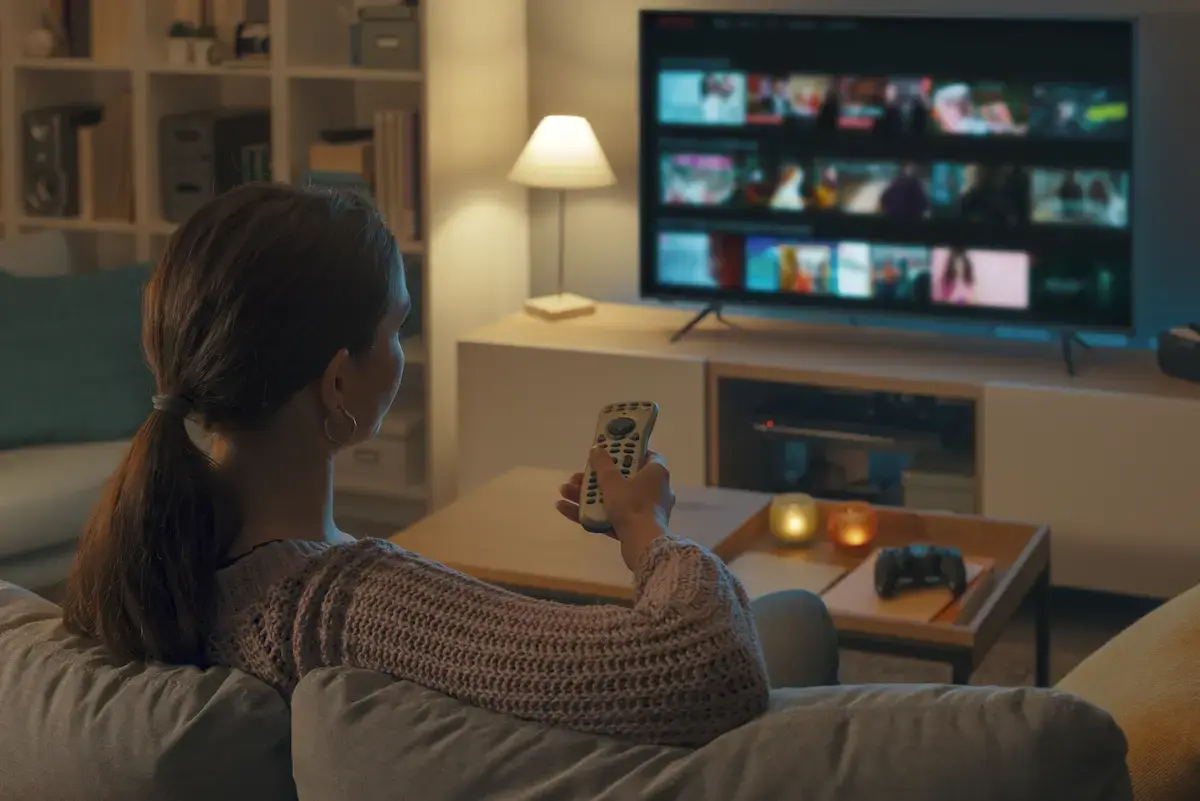 Off-duty per diem nurse sitting down to watch a movie while holding a remote